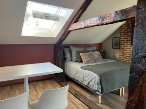 1 dormitorio con 1 cama y 1 mesa con sillas en La Madeleine, en Châteaugiron