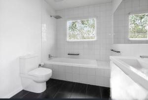 a white bathroom with a tub and a toilet and a sink at Luxe Private 2 bedroom cottage full kitchen in Healesville