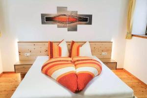 Una cama con almohadas naranjas y blancas. en Bertollhof en Silandro