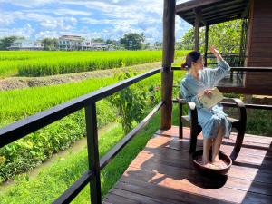 ナーンにあるPang Chompuの田んぼを見ながら椅子に座っている女性