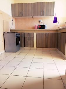 una cocina vacía con armarios de madera y suelo de baldosa blanca en Bliss homestay apartment with swimming pool en Mtwapa