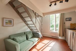 - un salon avec un canapé vert et des escaliers dans l'établissement Charming Apartment in the Heart of Versailles, à Versailles