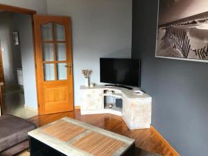 ein Wohnzimmer mit einem TV und einem Tisch in der Unterkunft Piso céntrico cerca de la playa in A Coruña
