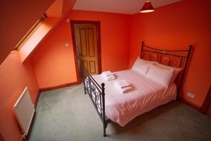 a bedroom with orange walls and a bed with white sheets at Woodlands House in Ballachulish