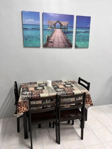 a dining room table with four paintings of a pier at 2 Bedroom house with Coway, all room air-cond, WIFI, Nettflix in Kampung Gurun