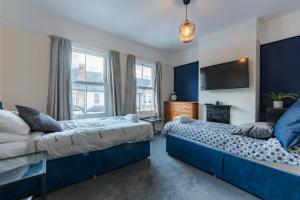 a bedroom with two beds and a flat screen tv at Springfield Place - 3 Bed Central Reading - Sleeps 6 - Free Parking in Reading