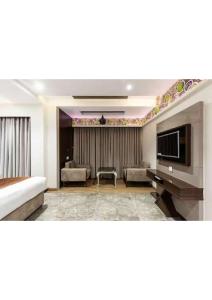 sala de estar con sofá y TV en Hotel Shivay President, en Ujjain