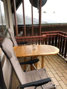 a wooden table and chairs on a balcony at Zu Hause am See - Pool, Sauna, Fitnessraum in Schluchsee