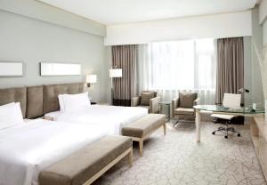 ein Hotelzimmer mit 2 Betten und einem Schreibtisch in der Unterkunft Holiday Inn Beijing Deshengmen, an IHG Hotel in Peking