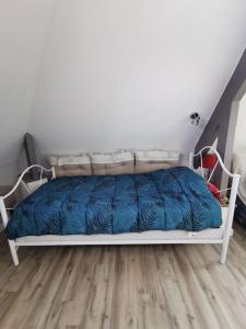 a white bed with a blue comforter in a bedroom at Catherine et Serge in Genêts