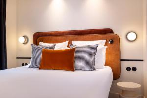 a bed with orange and white pillows on it at Hotel Chavanel in Paris