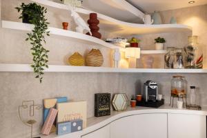 パリにあるホテル シャヴァネルの白い棚と植物と本が備わるキッチン