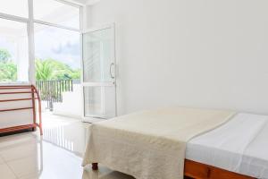 a white bedroom with a bed and a large window at Pavulak in Weligama