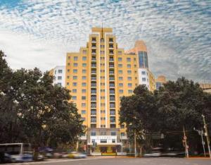 ein großes gelbes Gebäude mit wolkigem Himmel darüber in der Unterkunft Hengshan Garden Hotel in Shanghai