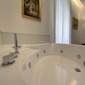 una vasca bianca in bagno con un dipinto di GUALTIERI B&b - LUXURY ROOMS a San Giorgio a Cremano