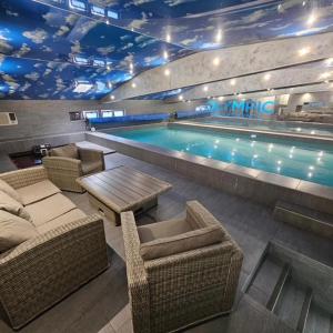 uma piscina com cadeiras de vime, uma mesa e uma piscina em Olympic Apartments Wellness & Spa em Belgrado