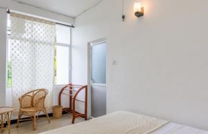 a bedroom with a bed and a window and a table and chairs at Pavulak in Weligama
