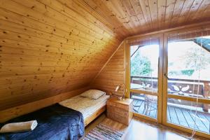 1 dormitorio con 1 cama en una habitación de madera con ventana en Domek Kołodziejówka Polanica Zdrój, en Polanica-Zdrój