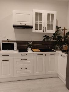 a kitchen with white cabinets and a microwave at Manoir de la Guignardiere : Thé ou café ? in Chavagne