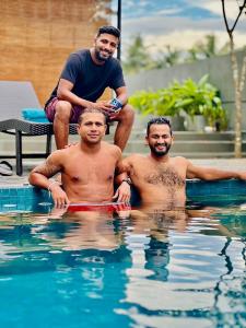 three men are sitting in a swimming pool at Container Villa Collection in Kadawatha
