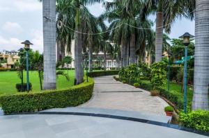 a walkway through a park with palm trees at Chinmay Hotel & Resort in Lucknow