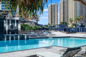 einen Pool mit Stühlen, Palmen und Gebäuden in der Unterkunft Three Bedroom, Level 57 - Circle on Cavill - Self Contained, Privately Managed Apartments in Gold Coast