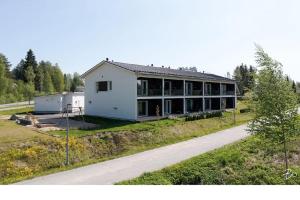 een groot wit huis met een weg ervoor bij Kotimaailma Apartments Sääksmäentie in Jyväskylä