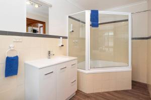 uma casa de banho com uma banheira, um lavatório e um chuveiro em Kitty's Cottages - Managed by BIG4 Strahan Holiday Retreat em Strahan