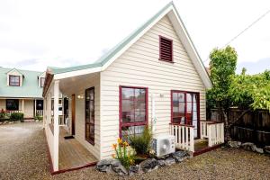 Casa blanca pequeña con ventanas rojas y valla en Kitty's Cottages - Managed by BIG4 Strahan Holiday Retreat, en Strahan