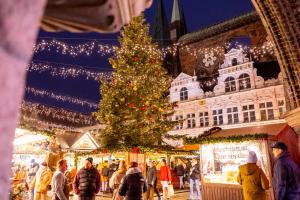 a christmas market with a christmas tree in front of a building at IntercityHotel Lübeck in Lübeck