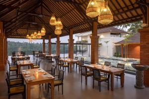 un restaurant avec des tables en bois, des chaises et des lumières dans l'établissement Tapa Agung View, à Menanga