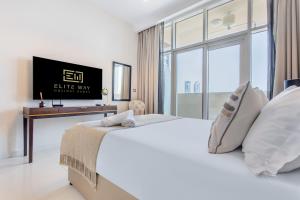 a white bedroom with a large bed and a tv at Cozy Haven Studio in Dubai