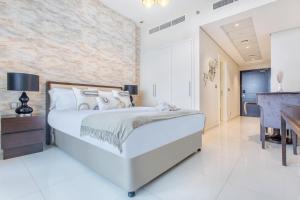 a white bedroom with a large bed and a desk at Cozy Haven Studio in Dubai