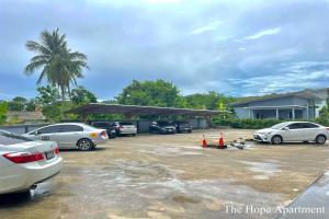 a parking lot with cars parked in front of a house at The Hope Apartment in Ban Chang