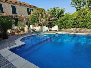 een groot blauw zwembad met twee stoelen en een huis bij La Vigne Blanche Gîtes in Lamotte-du-Rhône