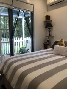 ein Schlafzimmer mit einem Bett und einem großen Fenster in der Unterkunft Kookaburra Cottage in Bowral