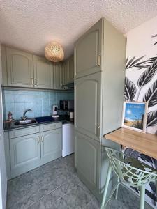 eine Küche mit weißen Schränken, einer Spüle und einem Kühlschrank in der Unterkunft Splendide vue à 180 sur l’océan in Lacanau