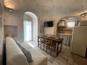 una cucina e una sala da pranzo con tavolo e frigorifero di SUITE - Trullo Relax sul Monte a Cisternino