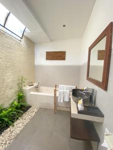 a bathroom with a bath tub and a sink and a bath tub at Villa Vidya Managed by Manara in Seminyak