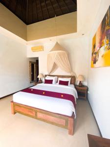 a bedroom with a large white bed with red pillows at Villa Vidya Managed by Manara in Seminyak
