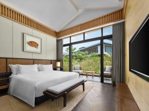 a bedroom with a large bed and a tv at Angsana Zhuhai Hengqing in Zhuhai