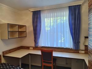 um quarto com uma secretária e uma janela com cortinas azuis em Wohnung - zur Länd em Moosburg