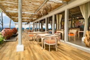 a restaurant with tables and chairs on a wooden floor at Nirwana Beach & Resort in Candidasa