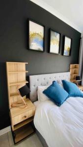 1 dormitorio con cama blanca y almohadas azules en BALLITO HILLS , 2 bedroom apartment, en Ballito