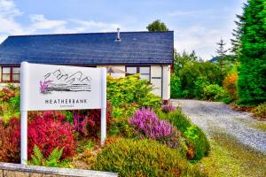 a sign in front of a house with flowers at Heatherbank Cottage in Onich +57 photos