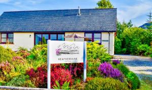 a sign in front of a house with flowers at Heatherbank Cottage in Onich