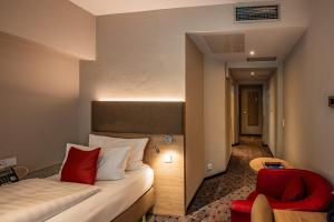 a hotel room with a bed and a red chair at AKZENT Hotel Villa Saxer in Goslar