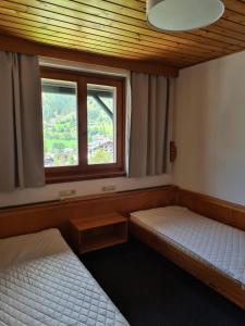 two beds in a room with a window at Mai-Brunn Alm Appartements, Maibrunnenweg 34-36 in Bad Kleinkirchheim