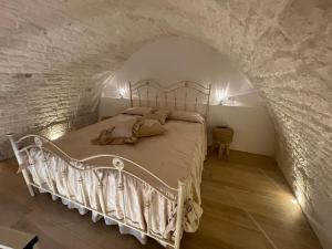 una camera con un letto bianco su un muro di pietra di SUITE - Trullo Relax sul Monte a Cisternino