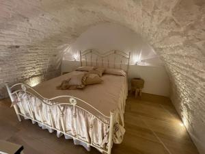 a bedroom with a white bed in a stone wall at SUITE - Trullo Relax sul Monte in Cisternino